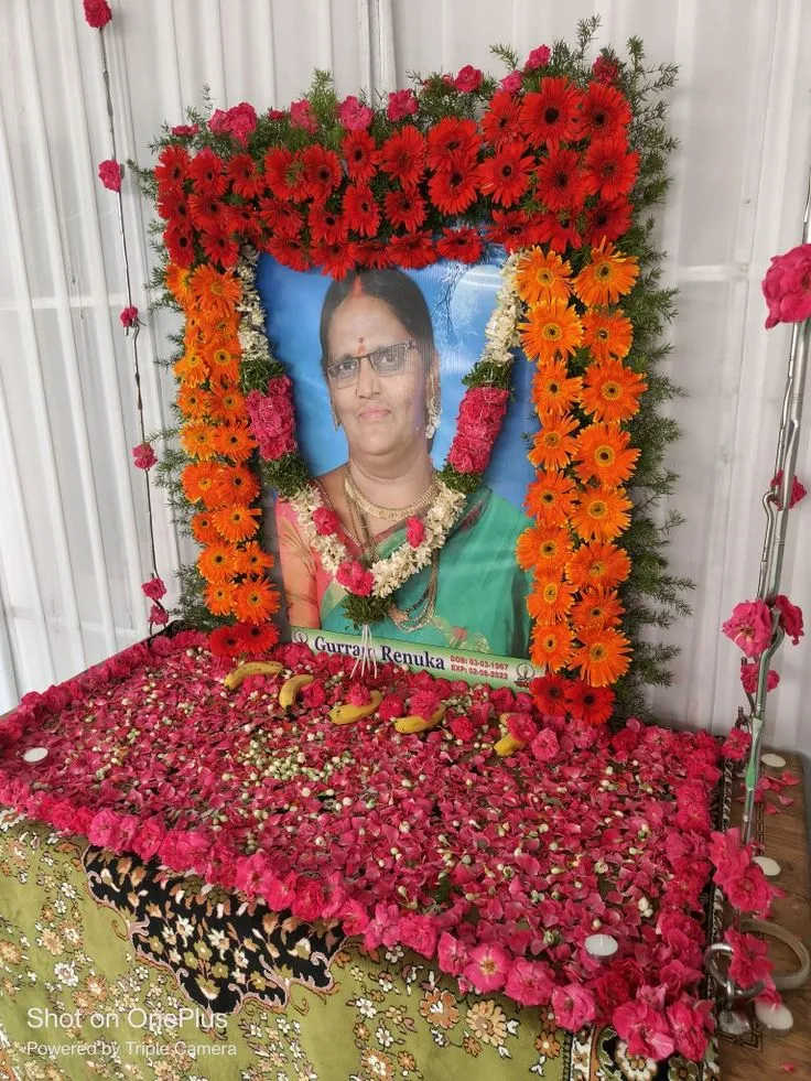 Ceremonial floral frame and flower-covered table arranged around a family memorial portrait