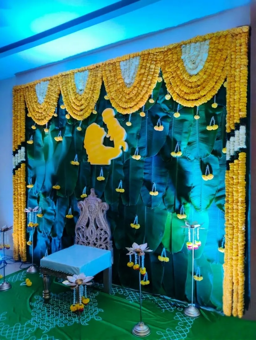 Leaf backdrop and marigold garlands with a mother-and-baby silhouette